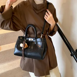 Glossy black tote bag with unique stitching, dual handles and a baseball charm detail