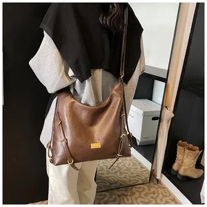Close-up of deep brown soft PU tote with golden hardware and adjustable side straps