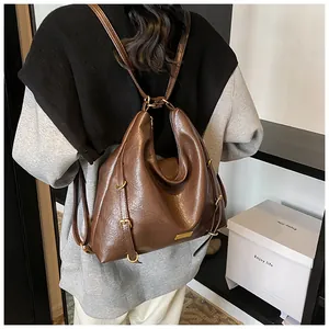 Detail of dark brown faux leather tote with golden hardware and brand logo on shoulder bag
