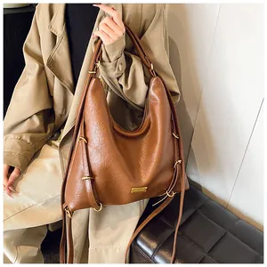 Close-up of brown textured leather tote bag with gold hardware and wide shoulder strap