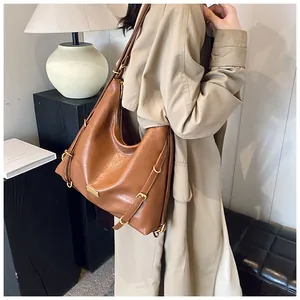Detail of a brown leather hobo bag with gold hardware and stylish side buckle accents