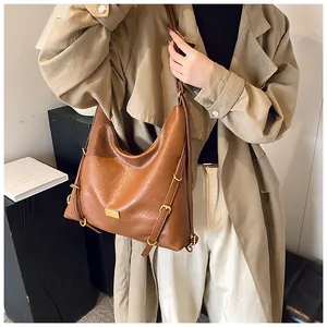 Detailed macro view of brown pebbled leather tote with golden buckle and logo plate