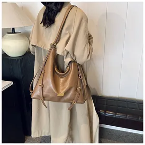 Detail of a large brown vintage hobo bag with a side metal buckle and a gold nameplate