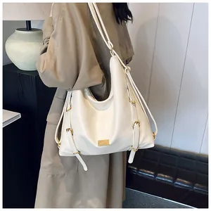 Detail of white textured leather tote with gold rings and adjustable drawstring side