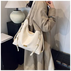 Detail of cream white oversized hobo bag with gold buckles and brand logo plaque