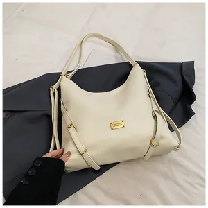 Detail of off-white tote bag with golden fashion metal plate on dark suit fabric