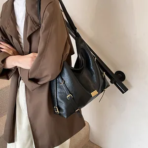 Black pebbled leather large tote bag with gold hardware shown on shoulder in interior setting