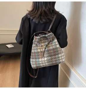 Details der karierten Tweed-Beuteltasche mit Lederriemen und Vintage-Stofftextur