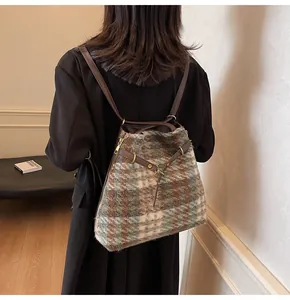 Detail eines Woll-Karo-Rucksacks mit braunen Lederriemen auf einem schwarzen Blazer