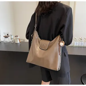 Detail of coffee brown oil wax leather tote bag with baseball charm and metal chain