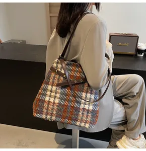 Detail der Tweed-Tasche mit Karomuster, braunem Lederriemen und goldener Schnalle am Model