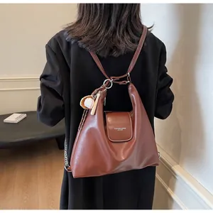 Detail view of brown leather hobo bag with unique baseball charm on shoulder strap