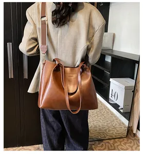 Detailed view of brown leather tote bag with wide adjustable strap for daily commute