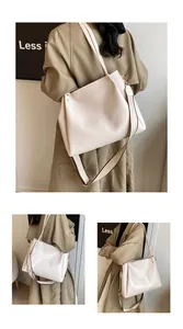 Detail of a large cream faux leather tote bag showing golden rivets and dual straps