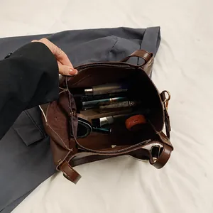 Interior view of large capacity dark brown tote bag showing cosmetics and zipper detail