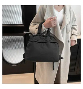 Side view of a black quilted puffer tote bag with drawstring closure worn by a model