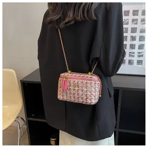 Dettaglio di una mini borsa a tracolla in tweed rosa con catena dorata e fiore decorativo