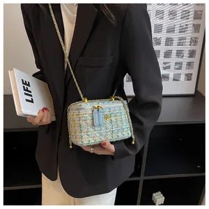 Dettaglio della trama in tweed colorato e dell'ornamento a fiore dorato sulla borsa