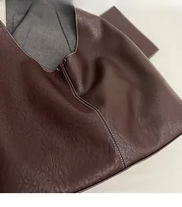 Close-up of soft burgundy leather tote with contrast stitching and matching pouch