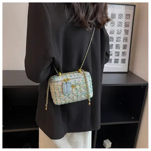 Détail du sac bandoulière en tweed avec camélia doré et bandoulière en chaîne tressée