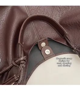 Detail of soft brown pebble leather tote bag featuring white stitching and magnetic closure
