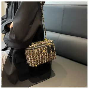 Dettaglio della borsa a tracolla in tweed con chiusura a camelia dorata su blazer nero