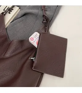 Detail view of brown leather tote bag set with a matching pouch and contrast stitching