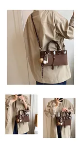 Detail of vintage brown tote bag showing contrast textures and baseball keychain charm