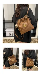 Détail du sac seau marron en cuir vintage avec logo M et charme de mouton