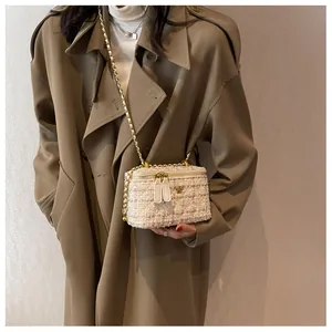 Dettaglio borsa a scatola in tweed con decoro floreale dorato e tracolla a catena