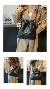 Vue détaillée d'un sac seau en cuir noir avec logo M doré et charme lion en peluche