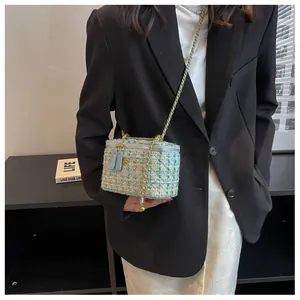 Détail d'un sac boîte en tweed avec bandoulière chaîne porté sur un blazer noir