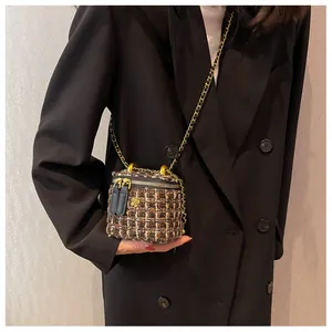 Dettaglio borsa a secchiello in tweed con camelia dorata e tracolla a catena su blazer