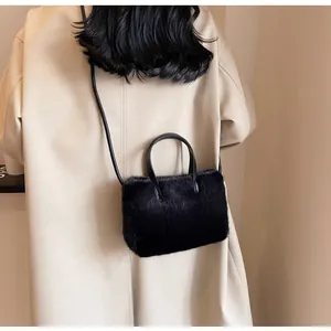Détail de la texture d'un sac à main en fausse fourrure noire avec poignée en cuir