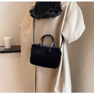 Détail de la texture en fausse fourrure noire du sac porté avec un trench-coat beige chic