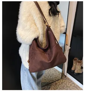 Dettaglio ravvicinato della borsa tote in pelle scamosciata marrone con fibbia d'oro