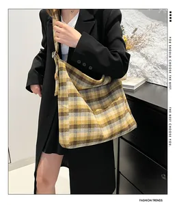 Detail of yellow and grey plaid canvas tote bag worn by a model in a minimalist room