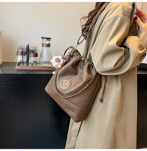 Détail du sac bandoulière en cuir marron avec logo M en métal et breloque mouton