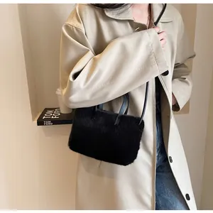 Détail d'un sac à main noir en peluche douce avec des anses fines en cuir élégantes