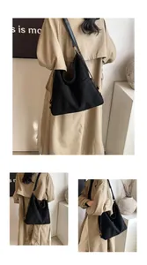 Dettaglio di una grande borsa hobo in tela nera con tracolla regolabile su modella