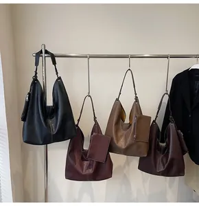 Detail of four matte leather hobo bags in assorted colors hanging on a display stand