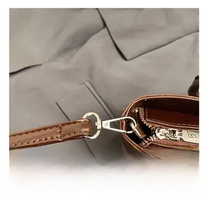 Detailed close-up of dark brown leather bag showing durable metal hooks and zipper