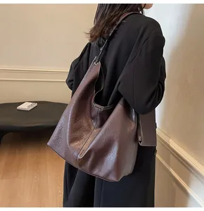 Detail view of large dark brown leather tote bag with white stitching and coin purse