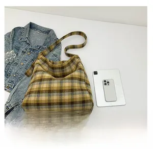 Detail view of the brown plaid tote bag comparing its large size with a tablet and phone