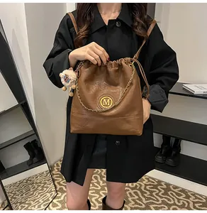 Détail d'un sac seau en cuir marron avec logo M doré et charmant mouton en peluche