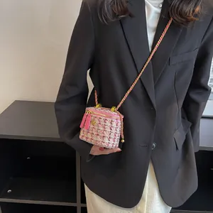 Mini borsa a secchiello in tweed rosa con tracolla a catena e fiore dorato indossata