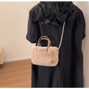 Détail d'un petit sac en peluche marron clair avec bandoulière en cuir et fourrure douce