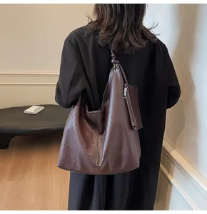 Detail view of large dark brown tote bag with white contrast stitching and accessory pouch