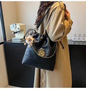 Détail du sac fourre-tout noir avec logo M doré, bandoulière chaîne et porte-clés mouton