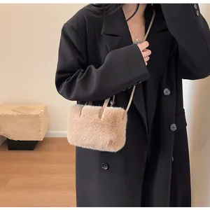 Vue détaillée du sac à épaule en peluche beige porté avec un blazer noir élégant